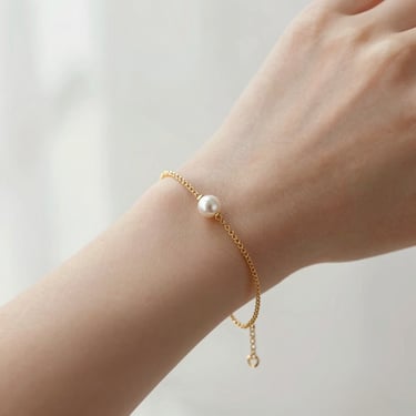 Close-up of a delicate gold chain bracelet on a woman's wrist, soft morning light, shallow depth of field.