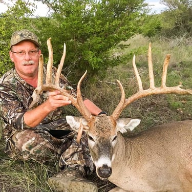 Hunter posing with a large 170 plus class trophy whitetail buck in the Mason County Texas Hill Country.