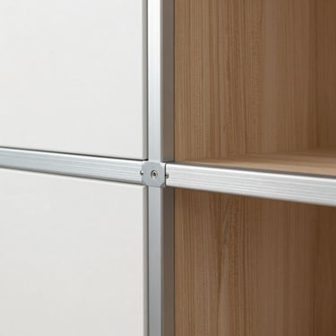 Straight-on detail of a modular kitchen cabinet joint, brushed metallic aluminum framework, natural daylight