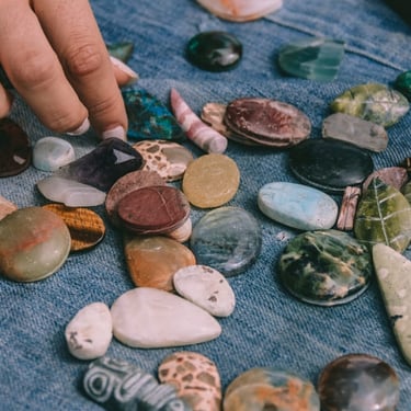 Diversas piedras preciosas de colores, una mano selecciona una de esas piedras 