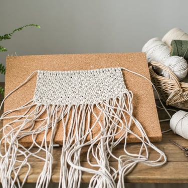 Tapete hecho de manera artesanal, sobre una mesa de madera con hilos de macramé