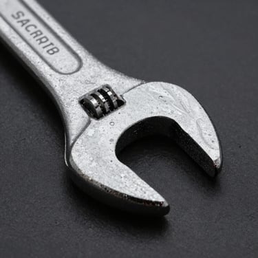Pristine forged steel wrench tool head, sharp directional studio lighting, high-contrast macro, 50mm