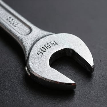 Macro shot of a pristine forged steel wrench head, sharp directional studio lighting, metallic textures