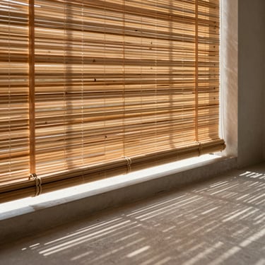 Premium bamboo blinds filtering warm sunlight onto a minimalist concrete balcony floor