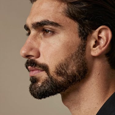 Elegant profile of a man with a perfectly defined, sharp and natural beard line, warm sophisticated lighting