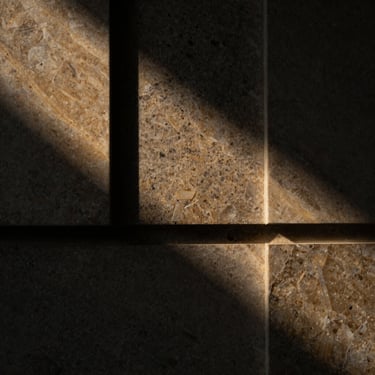 Extreme close-up of split-face quartzite wall cladding, dramatic raking light emphasizing deep shadows and sharp stone edges, 35mm.