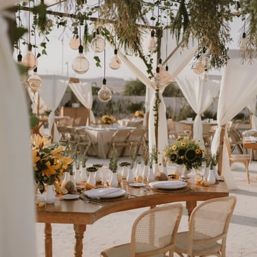 Mesa de boda al aire libre con decoración blanca y girasoles.