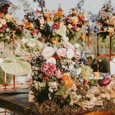 Arreglo floral abundante con rosas y flores silvestres en tonos variados.