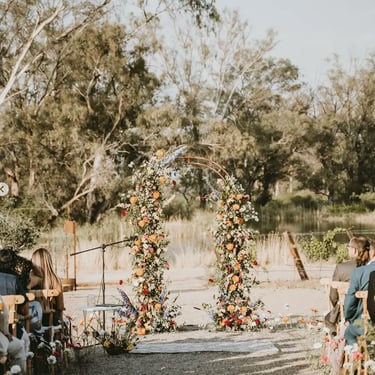 Arco floral decorando ceremonia en jardín natural.