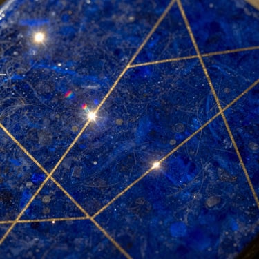 Close-up of lapis lazuli with fine gold geometric patterns, soft prismatic flares, ethereal lighting.