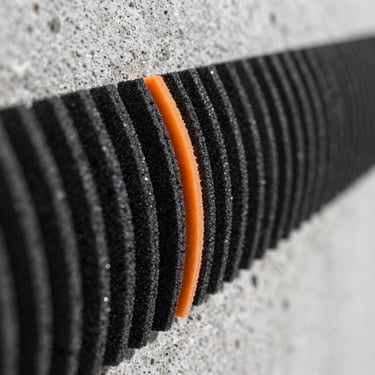 Extreme close-up of polymer-modified adhesive combed ridges on a concrete wall substrate, sharp focus