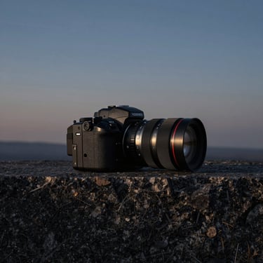 Moody outdoor landscape at dusk, technical gear on a dark granite ledge, high-contrast chiaroscuro lighting, square crop.