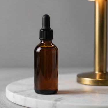 Dark glass bottle of pre-shave oil standing on white marble, warm brass sidelight from the right, oil surface catching the light, studio-controlled isolation shot, no background elements