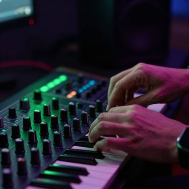 Close-up of hands tweaking synthesizer knobs in a dark studio, laser-green backlighting