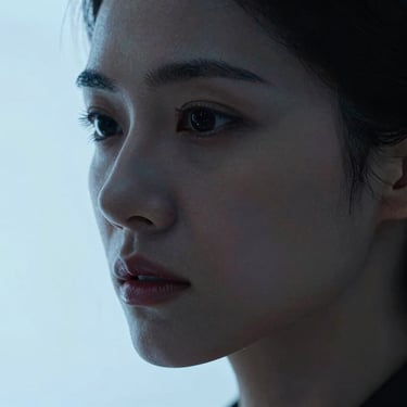 Chiaroscuro close-up of a woman with an intense expression, sharp jawline, shadowed face with cold blue edge light.