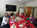 a grooup of several women authors sitting around a table filled with food and books at a Christmas party