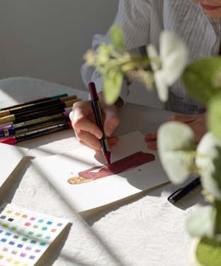 persona pintando un retrato estilo Live Art con rotuladores acrílicos en un día soleado