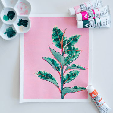 Fotografía de una ilustración colores verde rosa y crema de un ficus. Sobre la ilustración una paleta de cerámica y gouache