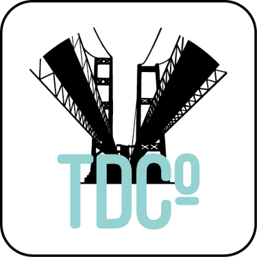 TDC Co logo featuring a black silhouette of a suspension bridge over light blue text.