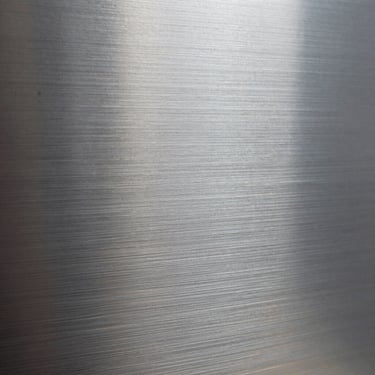 Extreme close-up of brushed aluminum paneling, showing the fine grain and metallic texture under crisp lighting