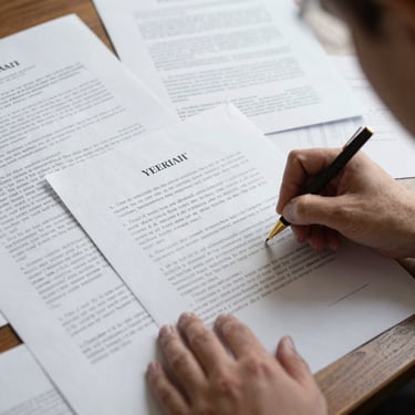 Mano firmando un documento legal sobre una pila de papeles