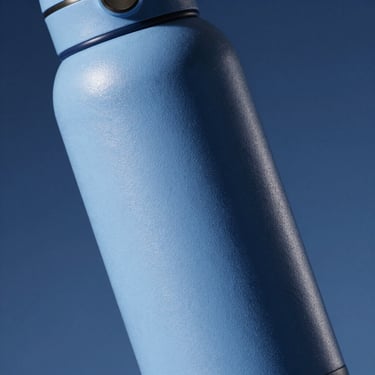 Close-up of a double-walled thermal bottle with a textured powder coating, soft blue-toned shadow, studio lighting