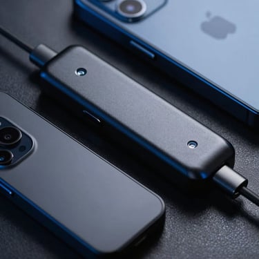 Close-up of sleek matte black aluminum electronic accessories with subtle blue reflections, crisp studio lighting, high contrast