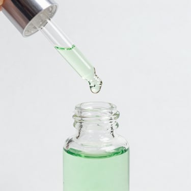 Macro shot of a clear glass serum dropper bottle with green fluid, pristine white laboratory background, soft daylight.
