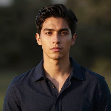 Serene portrait of a young Hispanic man, soft natural lighting, elegant dark background.