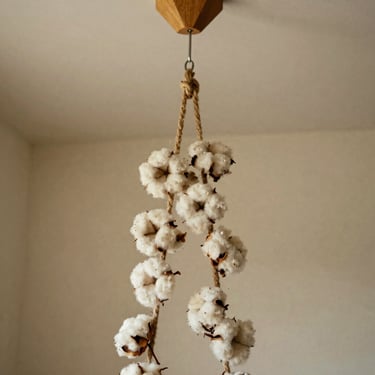 Bohemian cotton rope plant hanger suspended from a geometric wooden ceiling hook