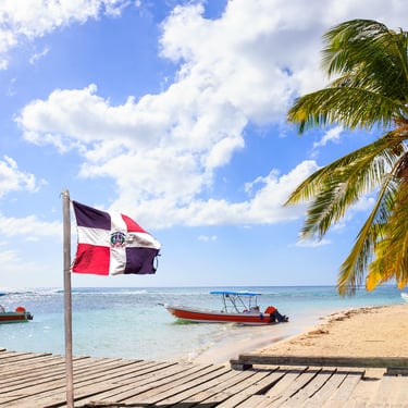 Saona Island Dominican Republic beach with flag palm trees boats and turquoise Caribbean sea