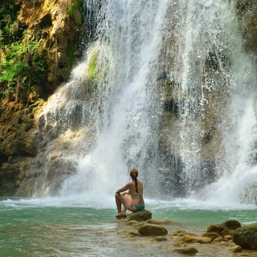 Woman relaxing at El Limón Waterfall surrounded by lush jungle in the Dominican Republic