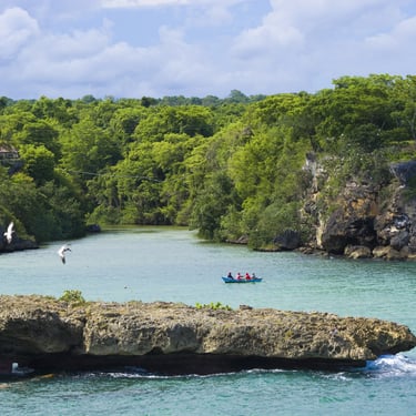 Boat on Boca de Yuma River surrounded by green cliffs and tropical trees in the Dominican Republic