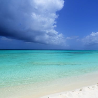 Storm clouds over clear turquoise water and white sand beach in the Dominican Republic
