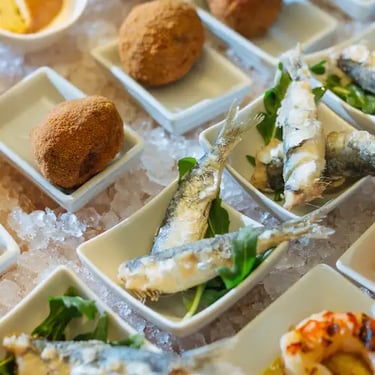 Selection of Venetian cicchetti, small seafood tapas with sardines, prawns, and fried meatballs served in traditional bacari 