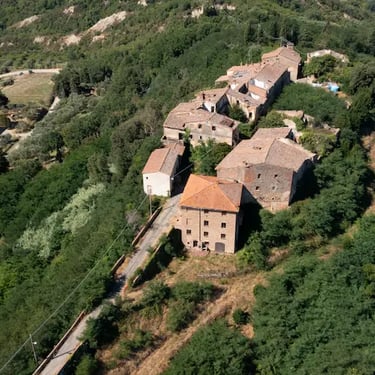 Aerial view of Toiano ghost village hidden in the Tuscan hills, surrounded by olive groves and countryside near Pisa