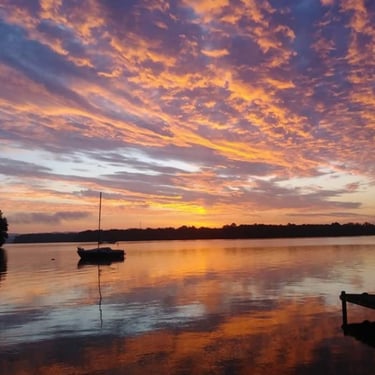 Sunrise with sailboat on lake
