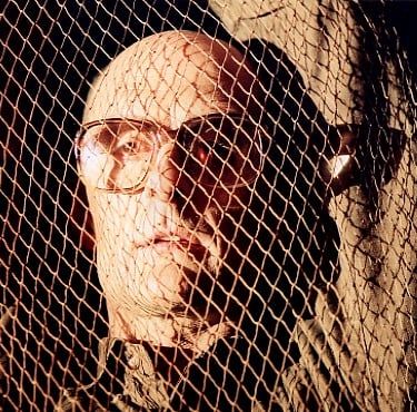 A middle-aged man with hands in the hair is trapped in a net
