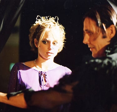 A beautiful young woman is led into a room by a sinister looking man wearing black