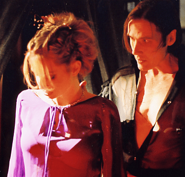 A beautiful young woman is led into a room by a sinister looking man wearing black