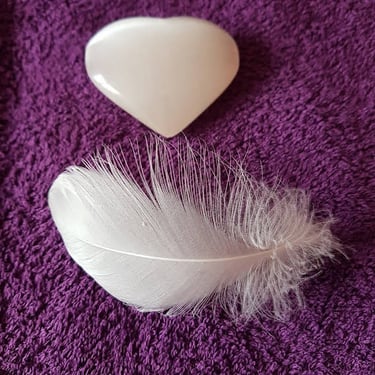 Heart shaped stone with white feather illustrating psychic reading peace and healing