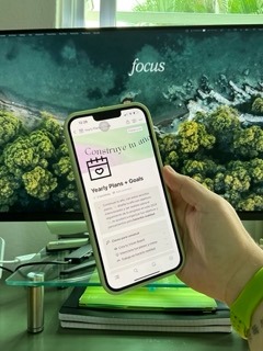 celular frente a un monitor enseñando una plantilla de notion de propósitos y metas