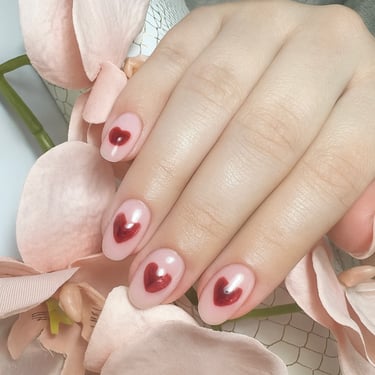 Nail art personalizado con corazones rojos sobre base nude. Diseño romántico y detallista realizado a mano