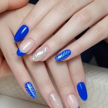 Diseño de uñas en azul eléctrico vibrante con detalles en foil de plata y dibujo de hojas azules. Manicura invernal 