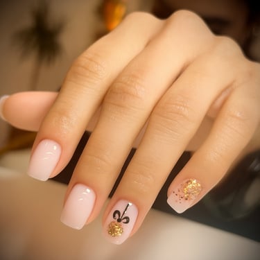 Diseño de uñas para Navidad y Nochevieja: base milky con lazo negro pintado a mano y detalle de esfera de glitter dorado