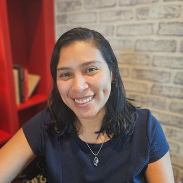Headshot image of Karen with a bookcase and brick wall background.