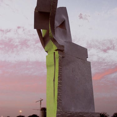 Large abstract marble sculpture bathed in shades of gray and neon green by a pink sunset sky.