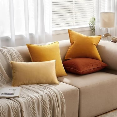 Cozy beige couch with mustard yellow, burnt orange, and cream velvet throw pillows