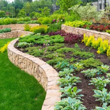 a backyard with a stone wall and plants on the terraces