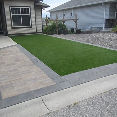 a front yard patio with a paver walkway and synthetic grass